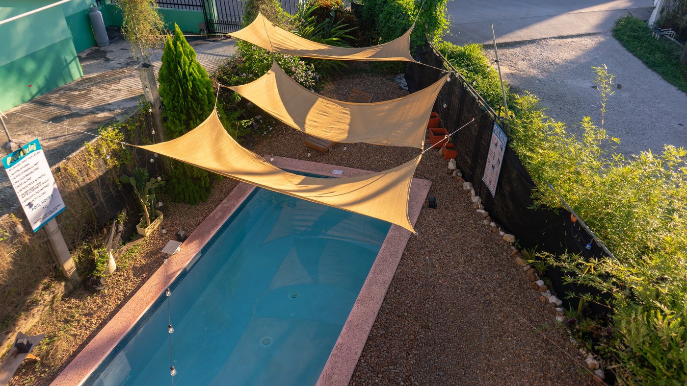 The guesthouse pool shaded by golden triangular shade sails.